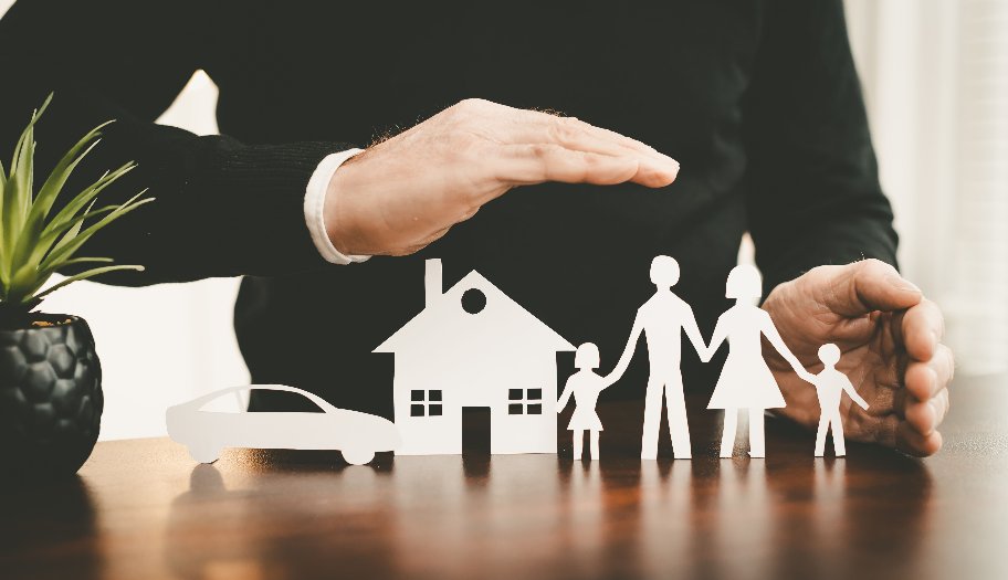 Assureur protégeant une famille, une maison et une voiture de ses mains